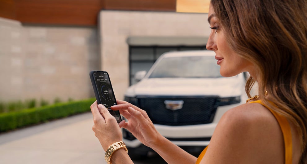 lady checking her mobile with a Cadillac vehicle background | Peterson Cadillac in BOISE ID